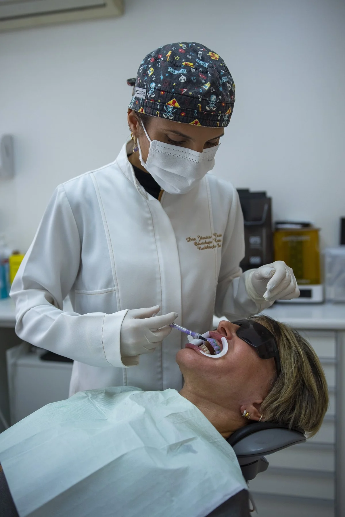 Aplicação de gel clareador com afastador e óculos de proteção